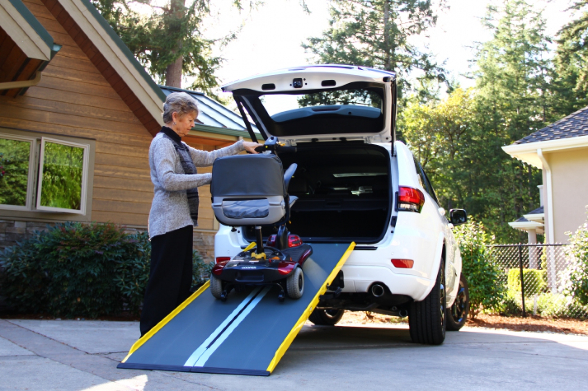 Woman loading a wheelchair into an SUV using a wheelchair ramp
